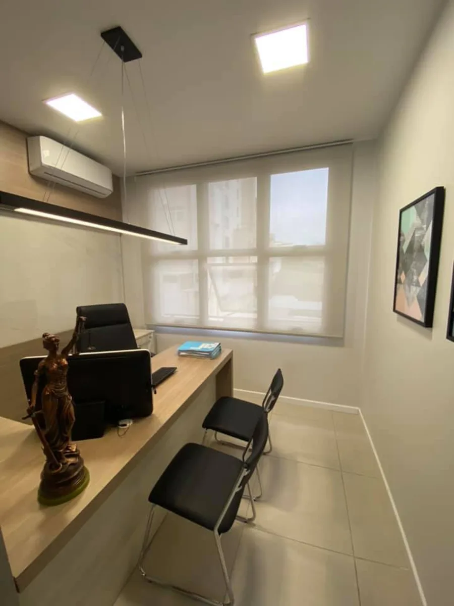 Sala de atendimento com mesa em L e cadeiras para clientes